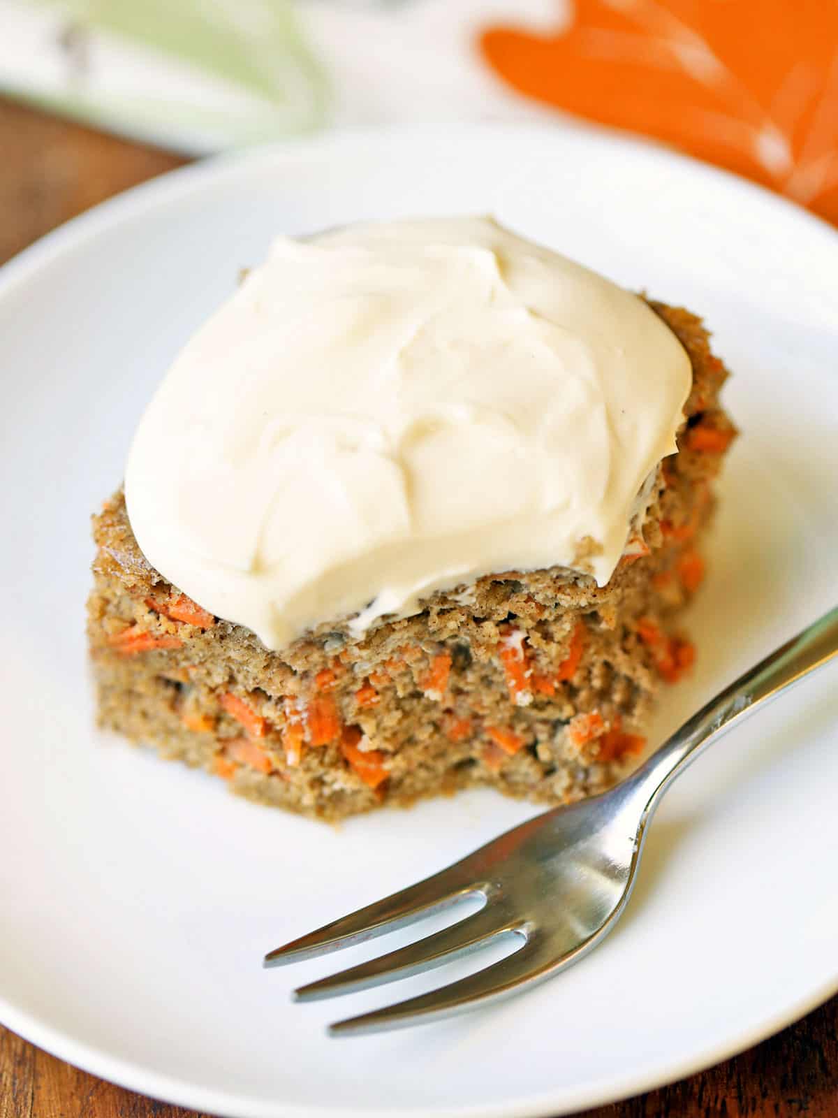 A slice of keto carrot cake served on a white plate with a fork. 