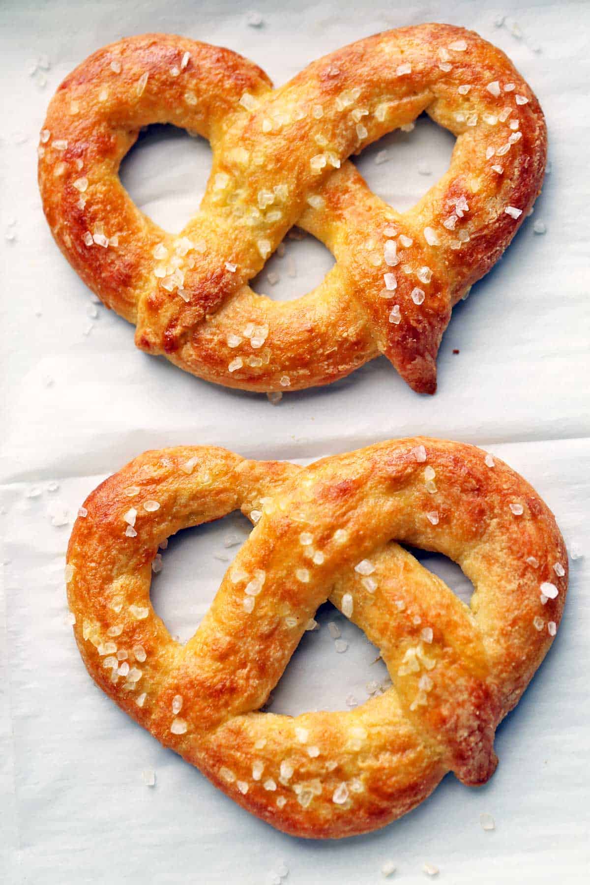 Two keto pretzels photographed on a parchment-lined baking sheet. 