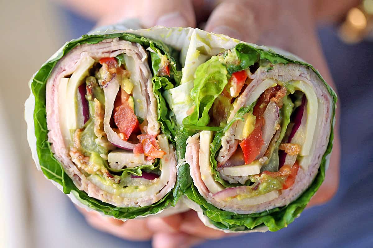Hands holding a cut-up lettuce sandwich. 
