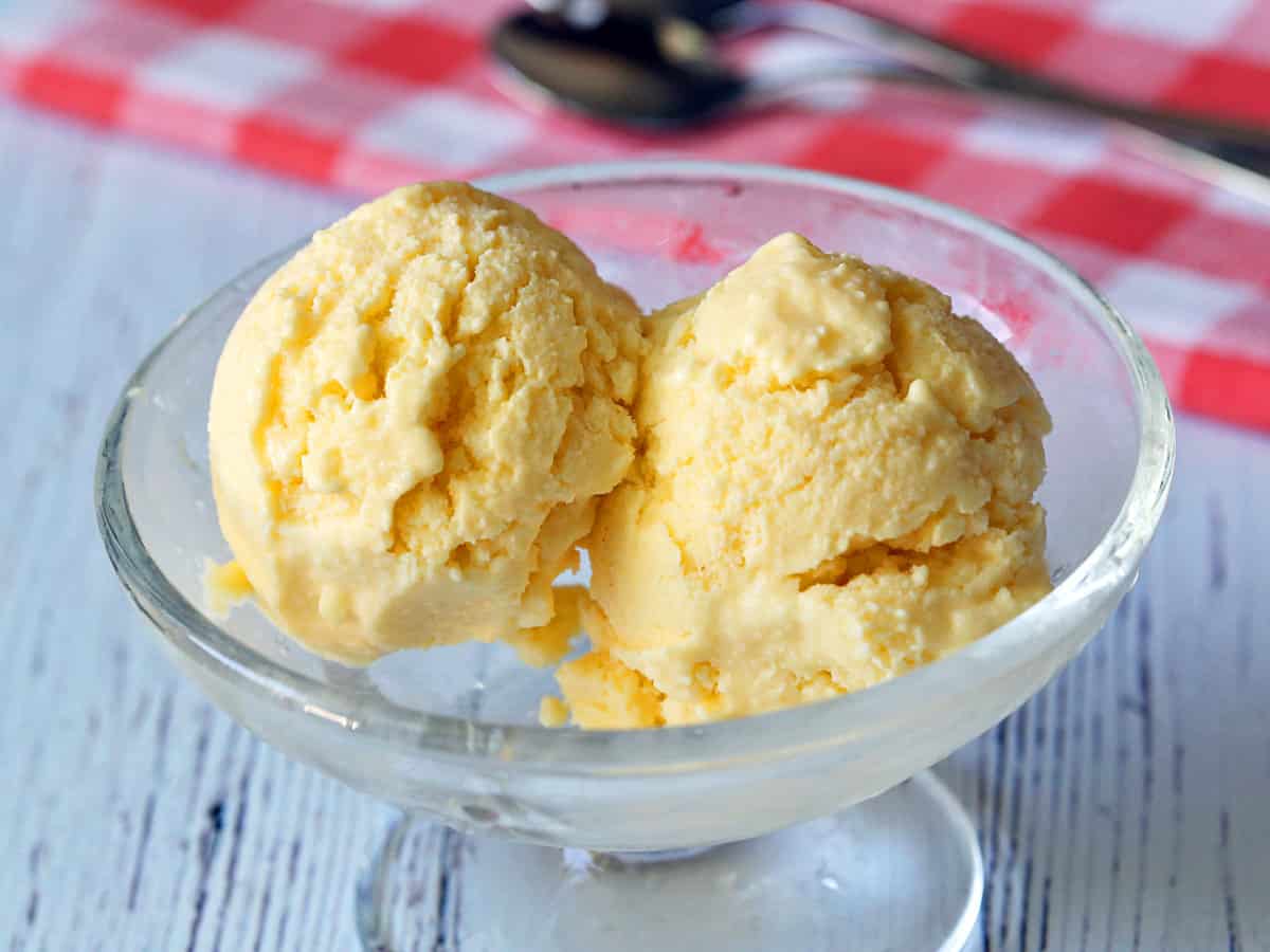 Dos cucharadas de yogur helado de mango servido en un plato de postre. 