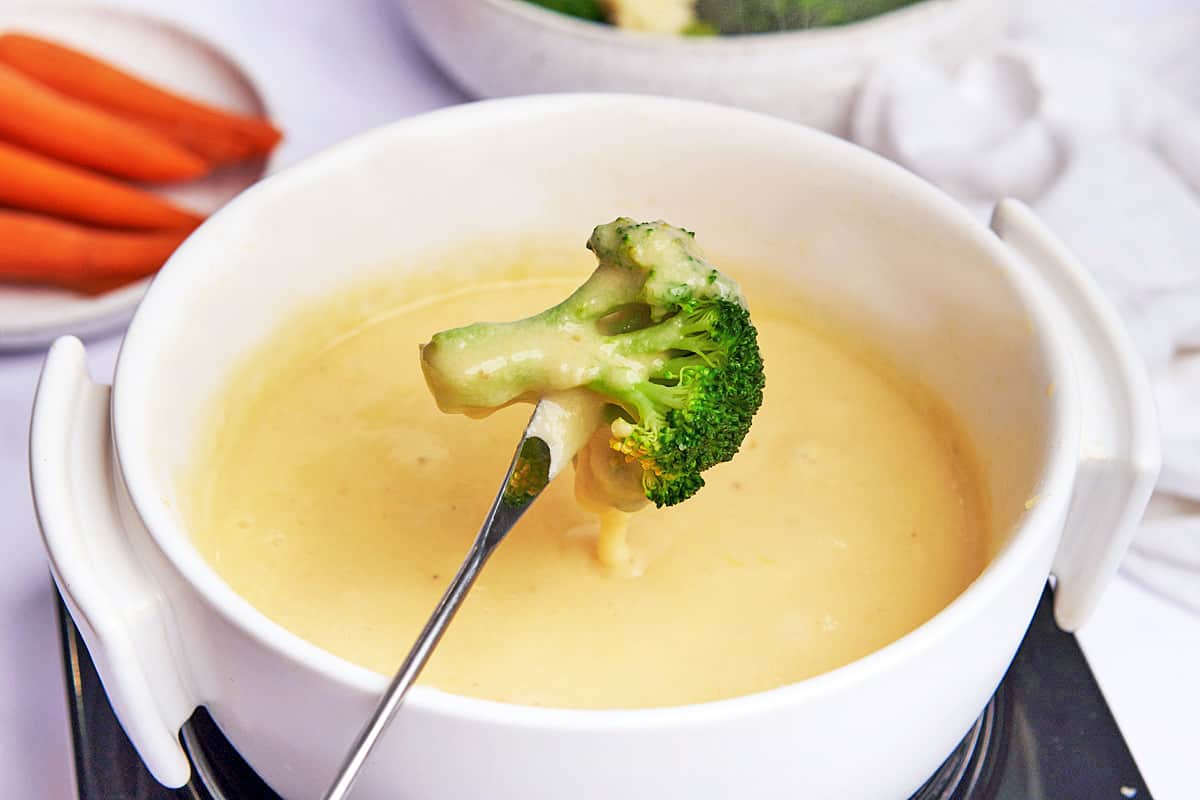 Broccoli floret dipped into a cheese fondue. 