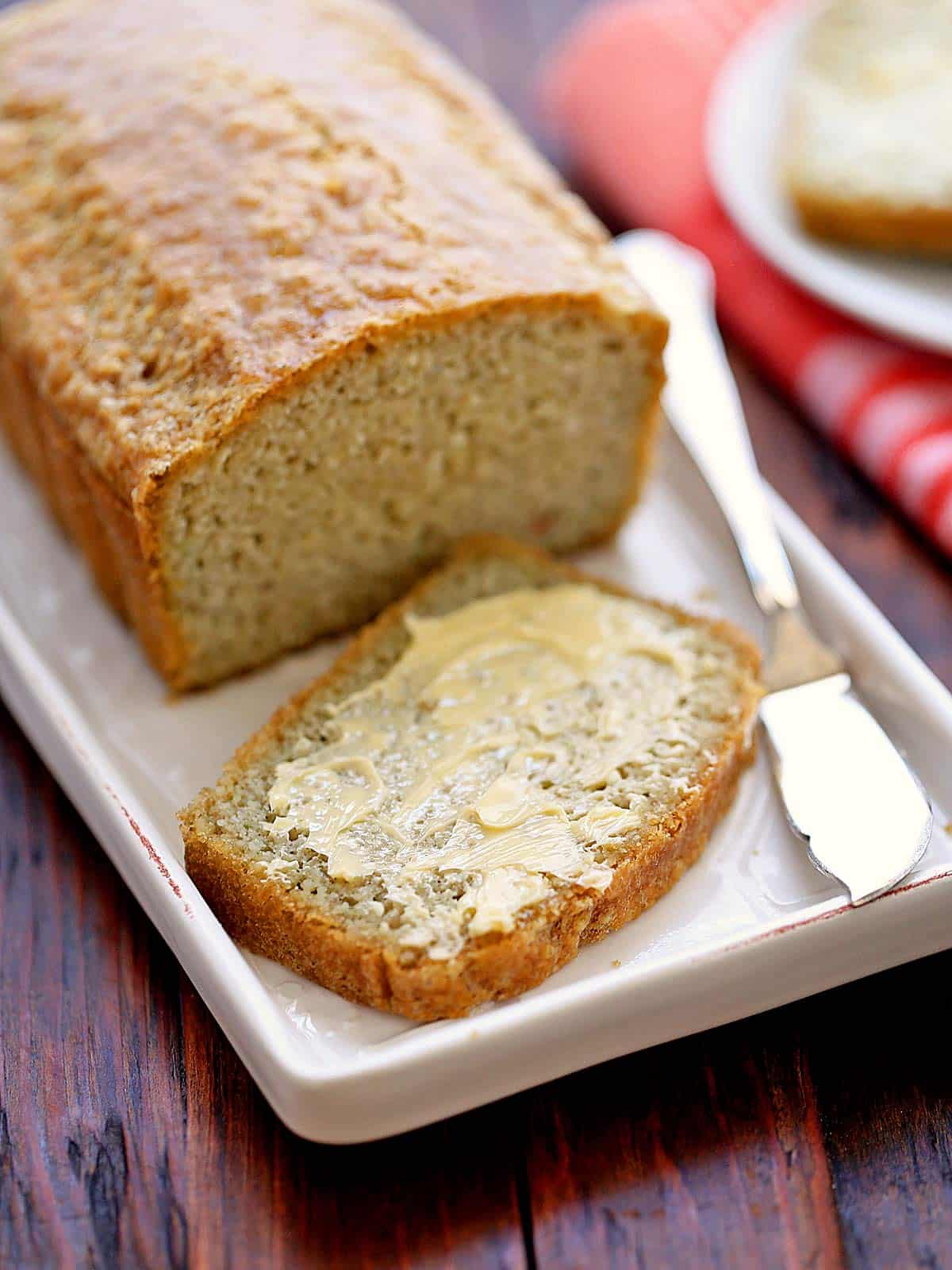 Almond flour bread, sliced, and the slice is topped with butter. 