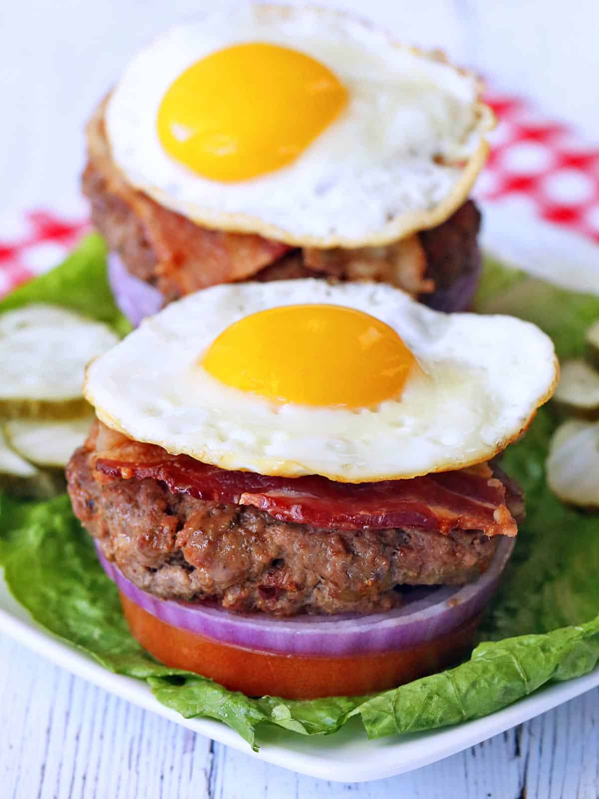 Two bacon burgers topped with fried eggs.
