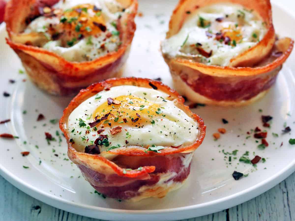 Three bacon egg cups served on a white plate. 
