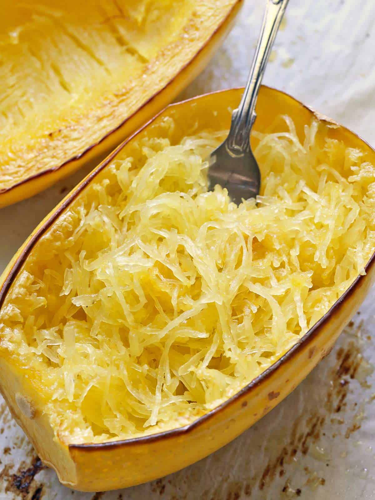 Baked spaghetti squash served on a baking sheet with a fork.  