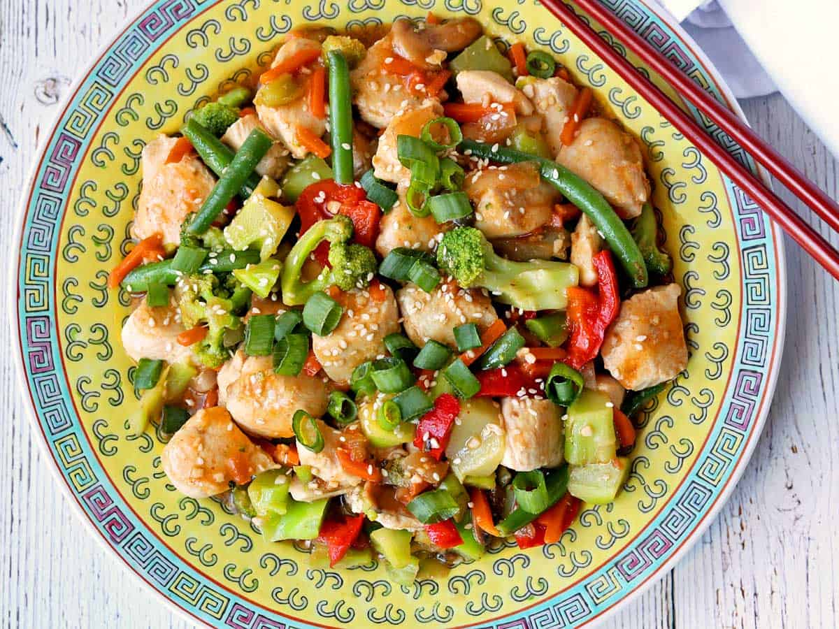 Chicken vegetable stir-fry served on a Chinese plate with chopsticks. 