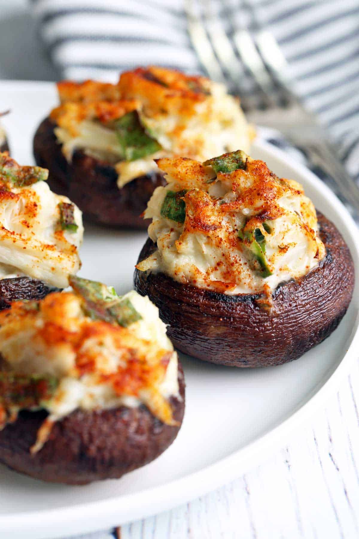 Crab-stuffed mushrooms served on a white plate. 