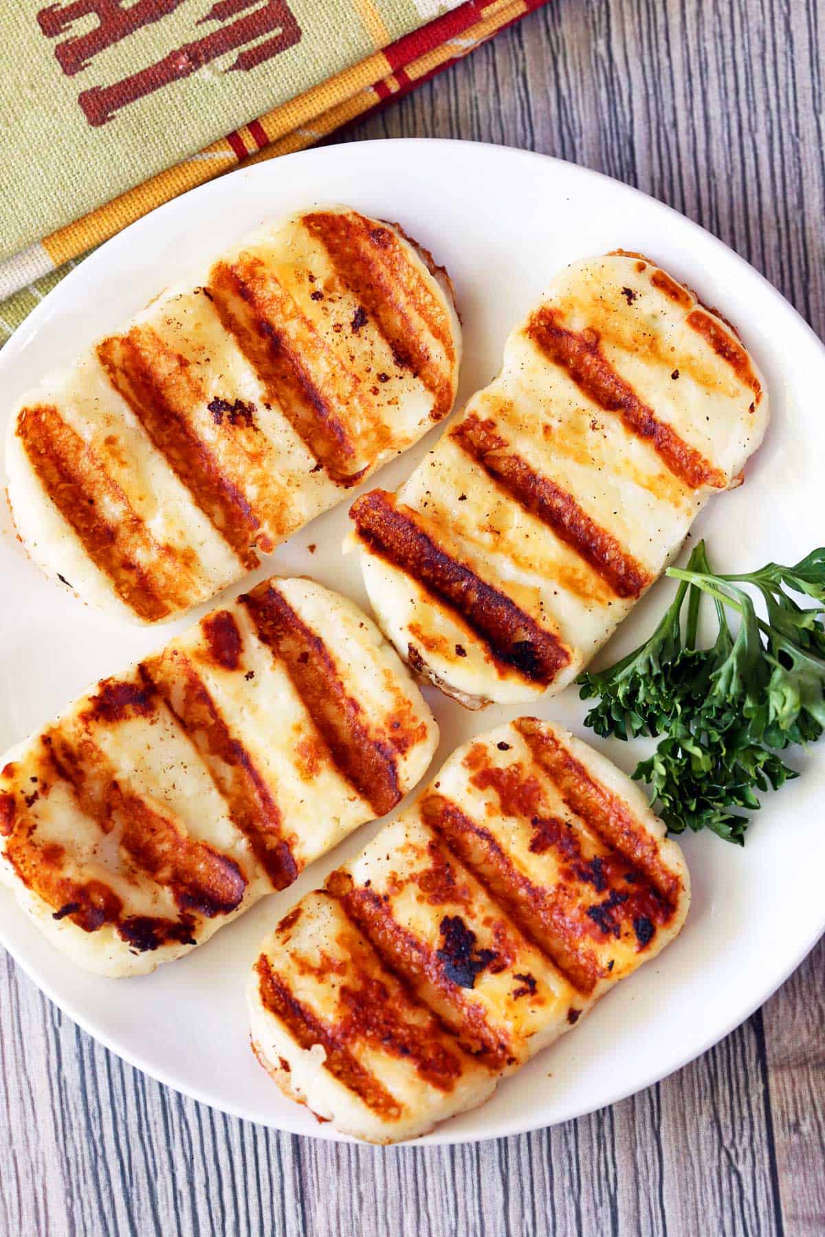 Four slices of grilled halloumi cheese served on a white plate. 