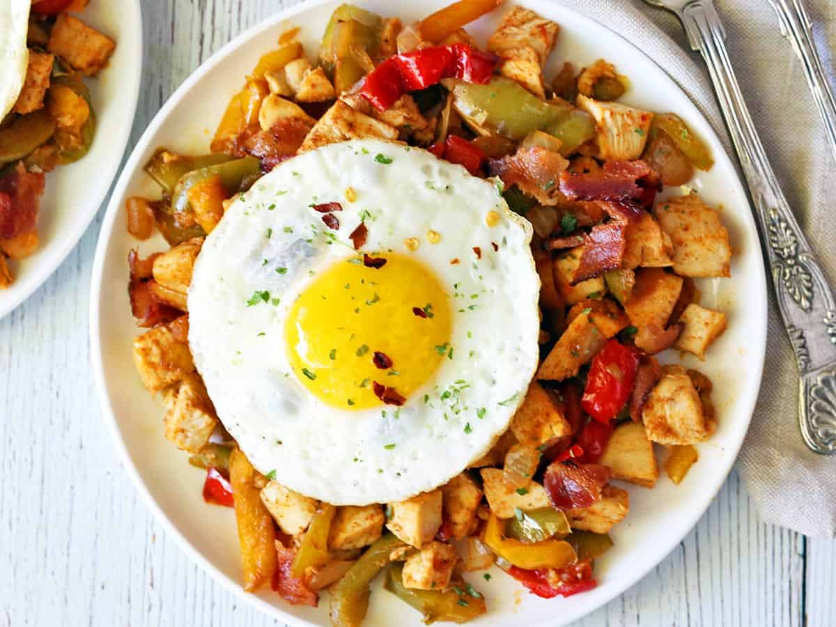 Turkey hash served on a white plate and topped with a fried egg. 