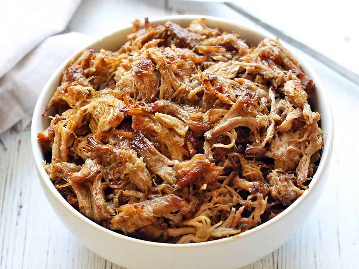 Slow cooker carnitas served in a white bowl. 