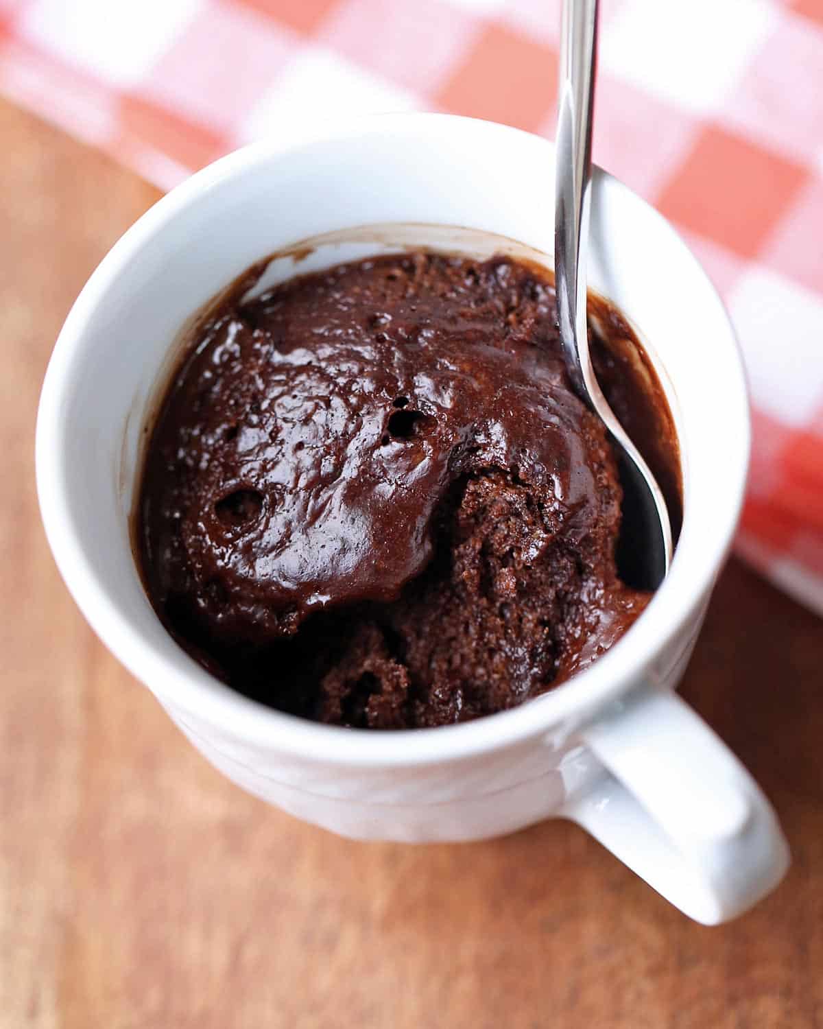 Keto chocolate mug cake served in a white mug with a spoon.