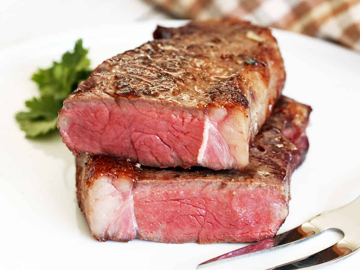 Reverse-sear steak, cut in two and served on a plate with a serving fork.