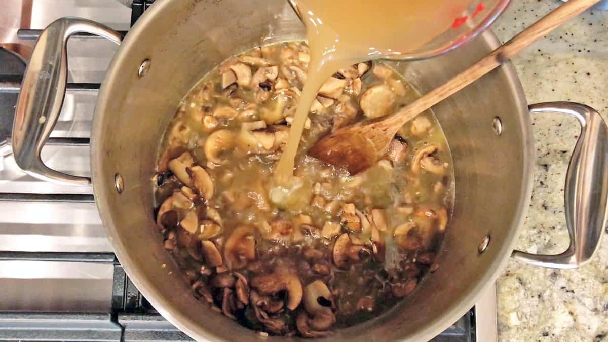 Adding broth to mushrooms in the stockpot. 
