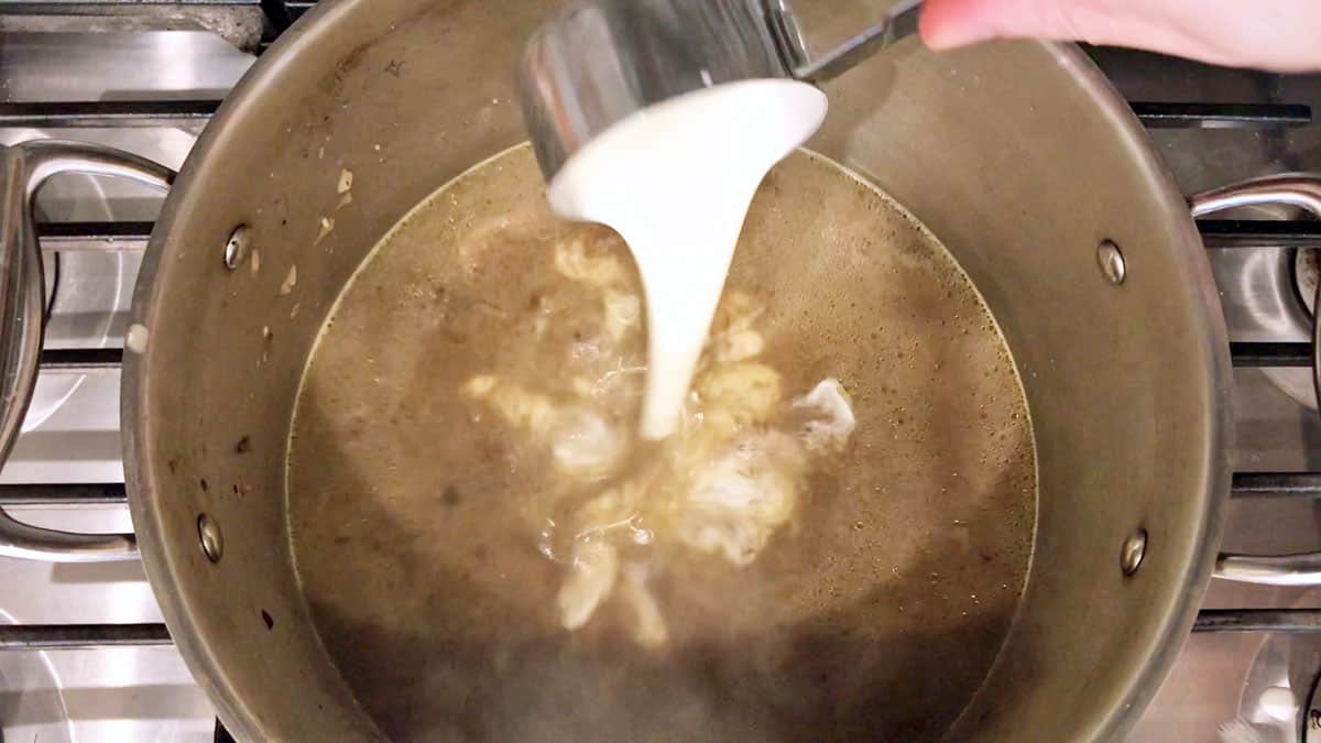 Adding heavy cream to the soup.