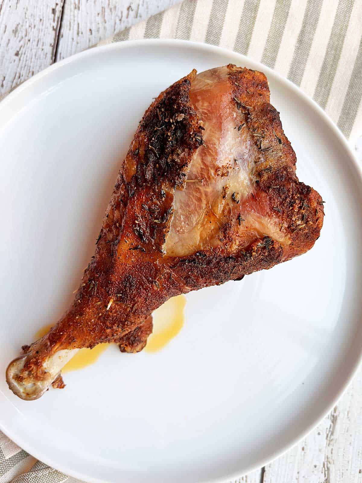 A large turkey drumstick served on a white plate. 