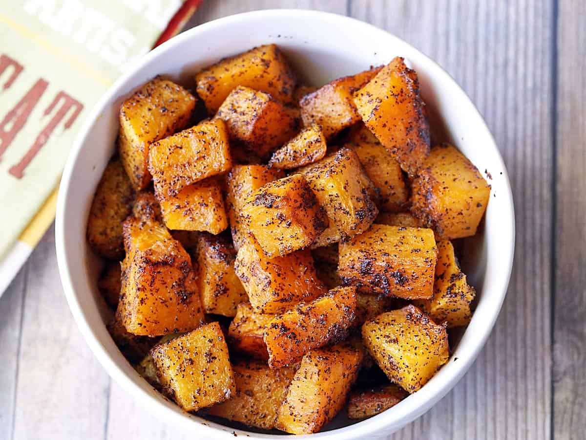 Roasted butternut squash cubes served in a white bowl. 