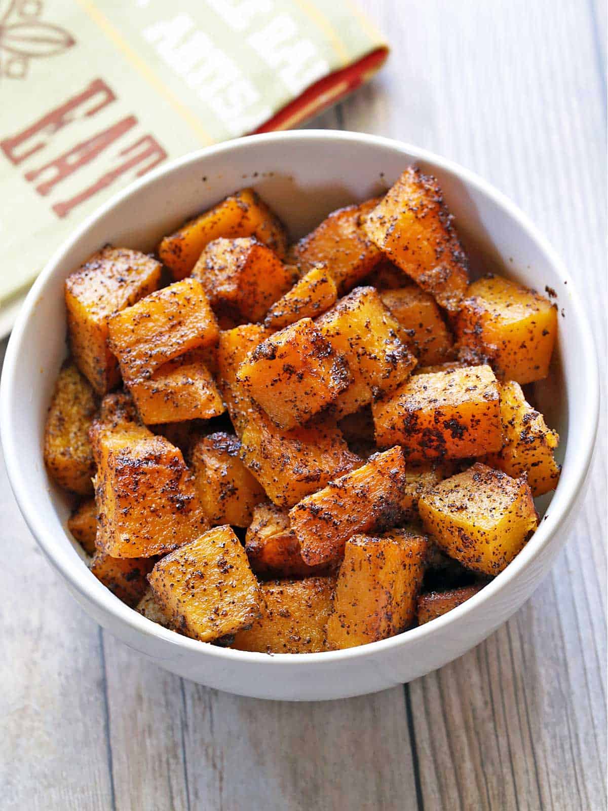 Roasted butternut squash cubes served in a bowl with a napkin. 