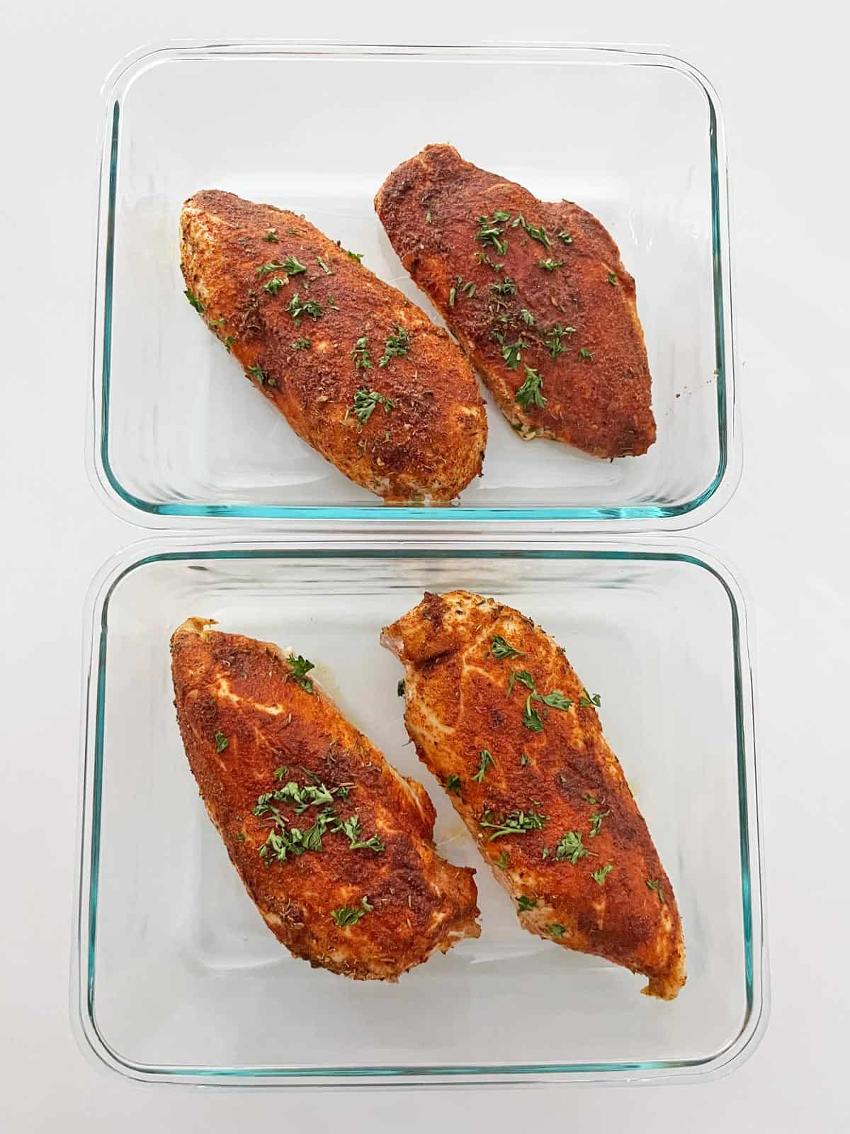 Storing Cajun chicken leftovers - the image shows two glass containers with two chicken pieces in each. 