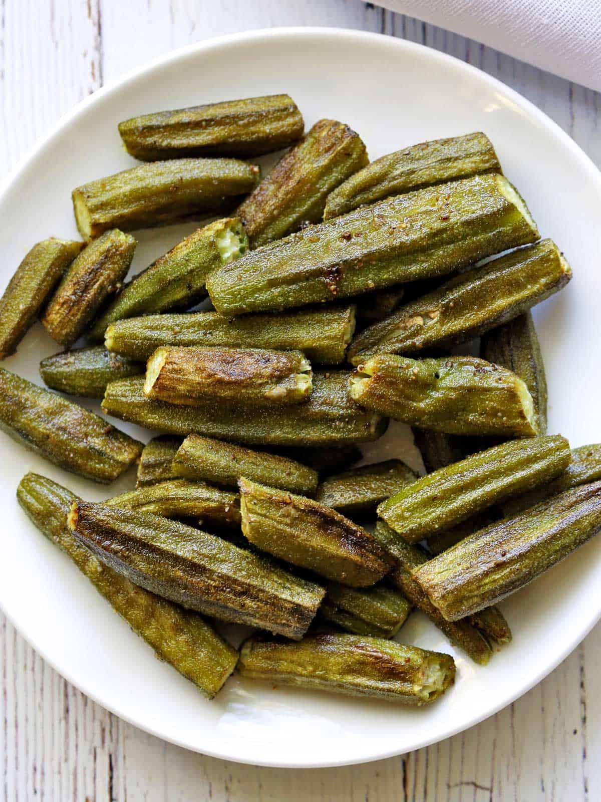 Roasted okra served on a white plate with a white napkin. 