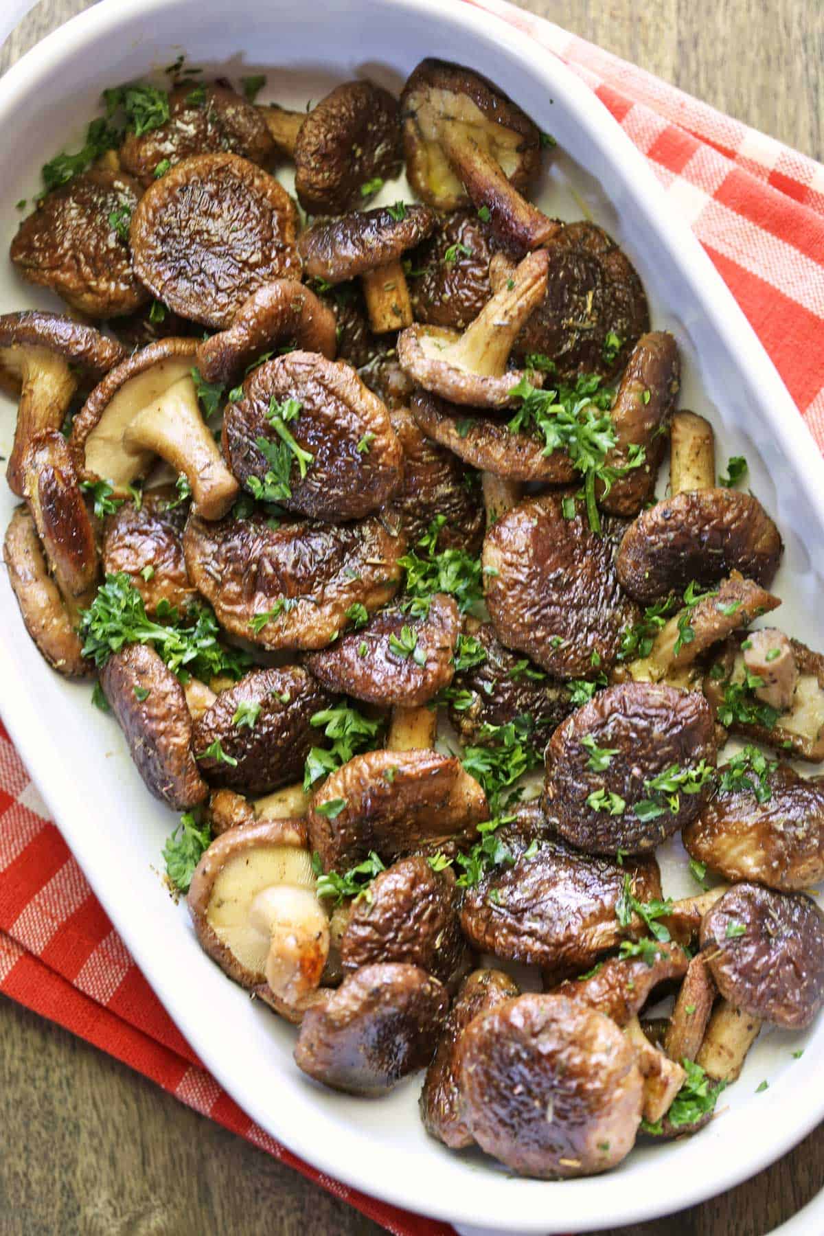 Baked shiitake mushrooms served in a baking dish and topped with parsley. 