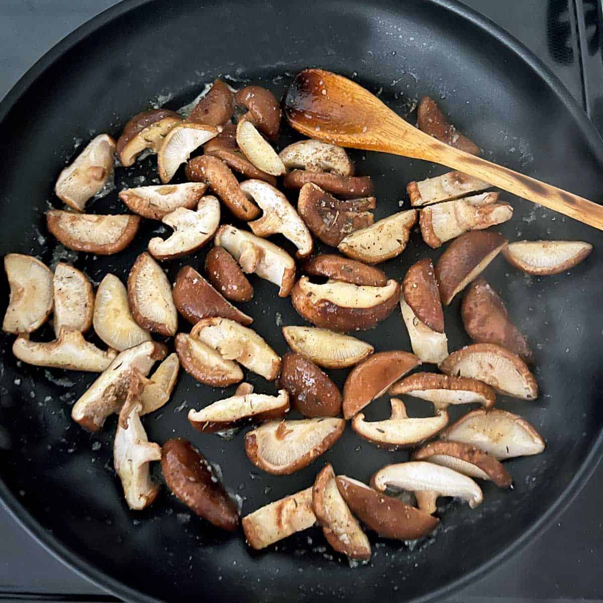 Sliced shiitake mushrooms in a skillet. 