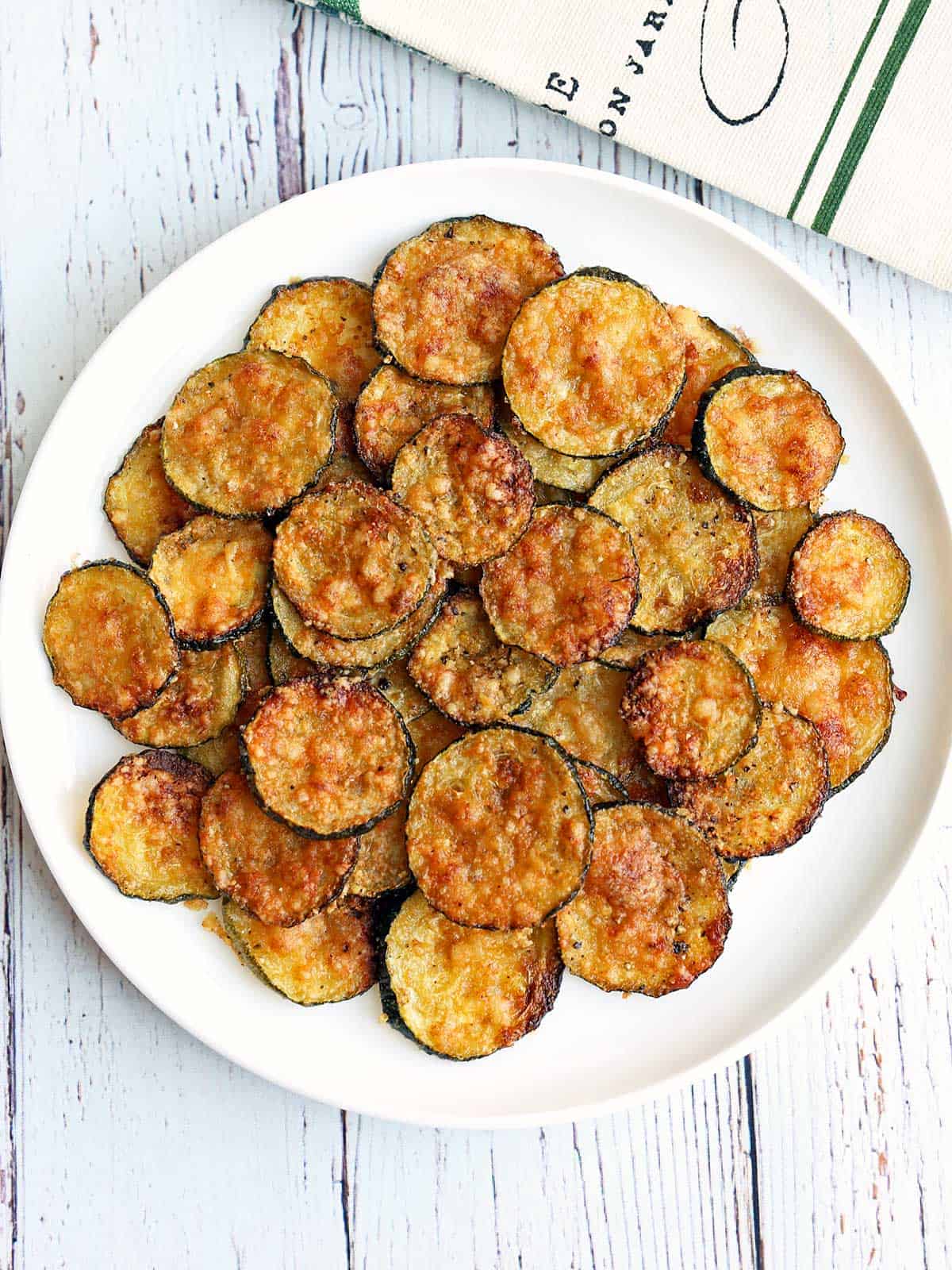 Zucchini chips served on a white plate. 