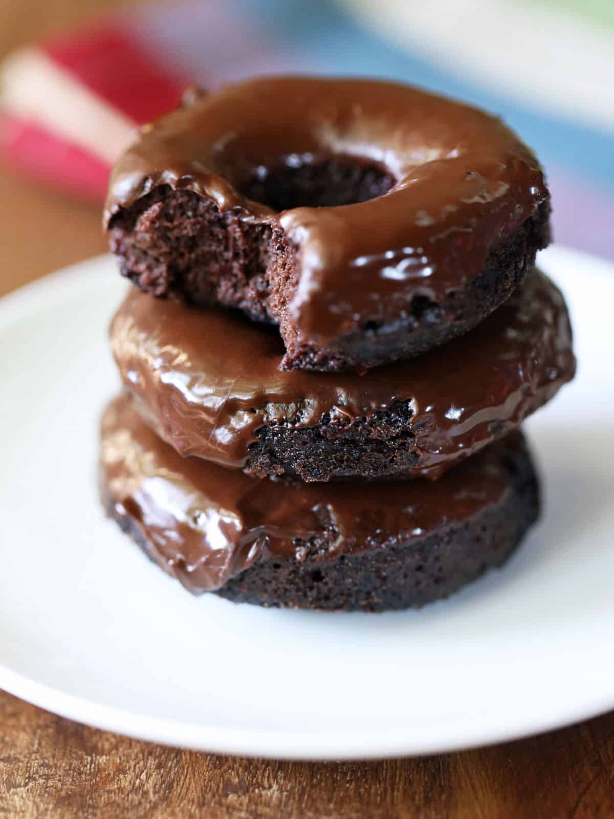 Three keto donuts stacked on a white plate.