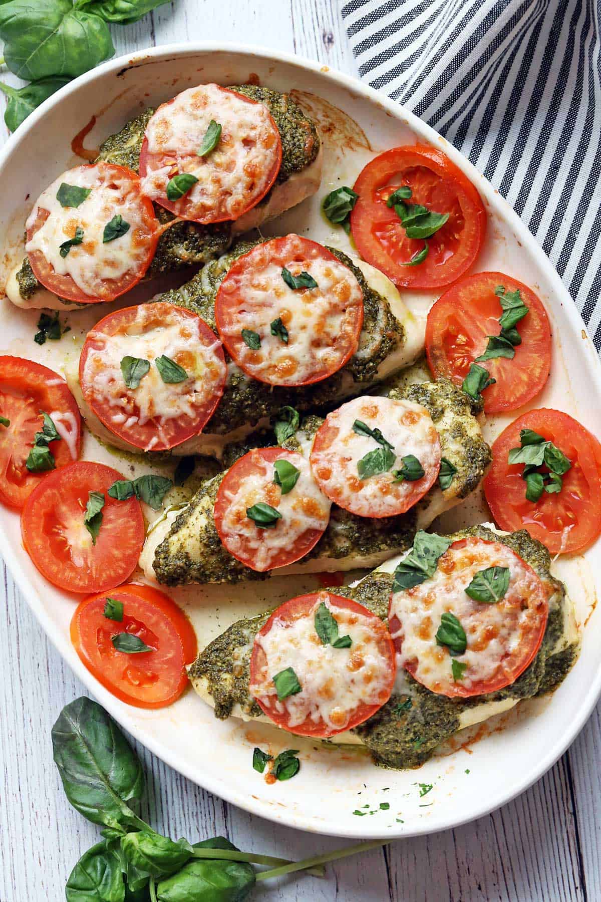 Pesto chicken served on a white platter, garnished with tomatoes. 