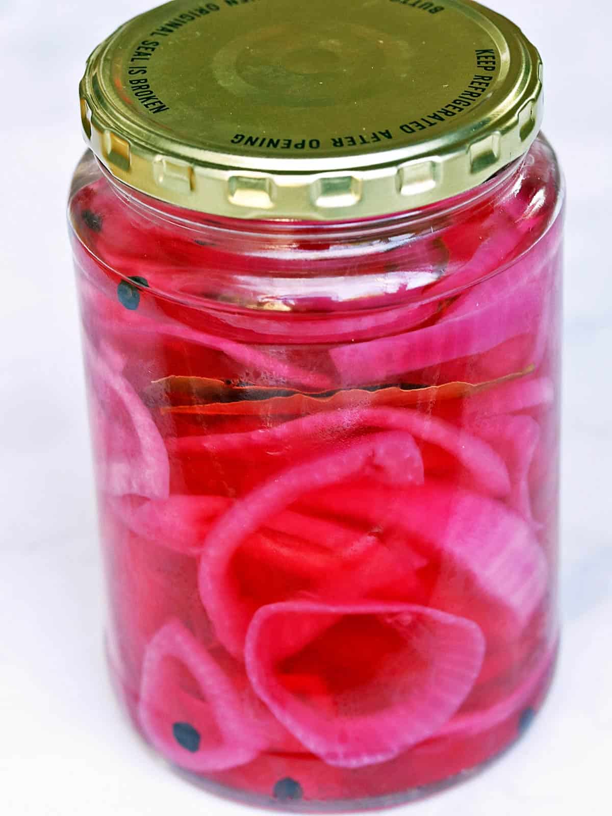 Pickled red onions served in a glass jar with a lid. 