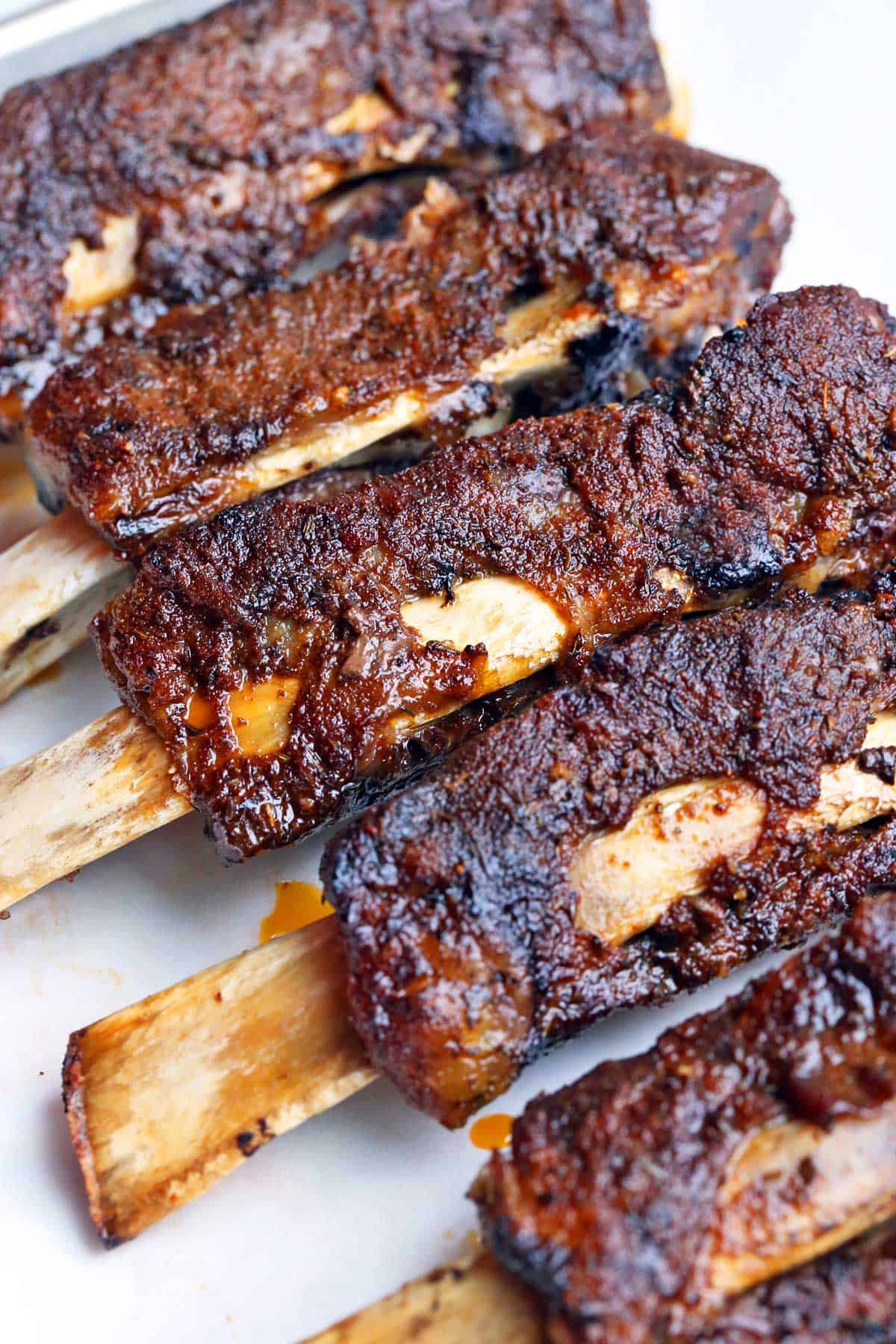 A close up of five cooked beef ribs with exposed bones. 