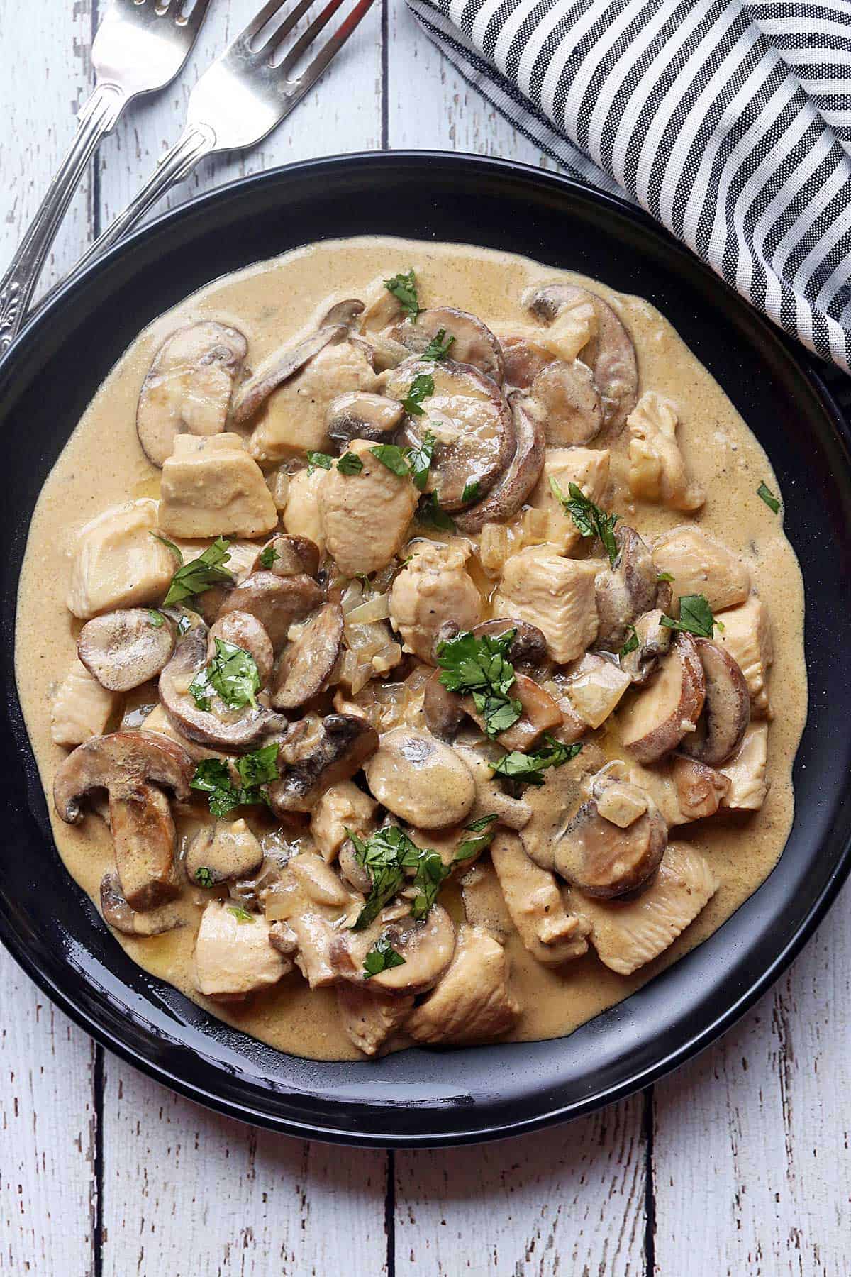Chicken stroganoff served on a black plate with a napkin. 