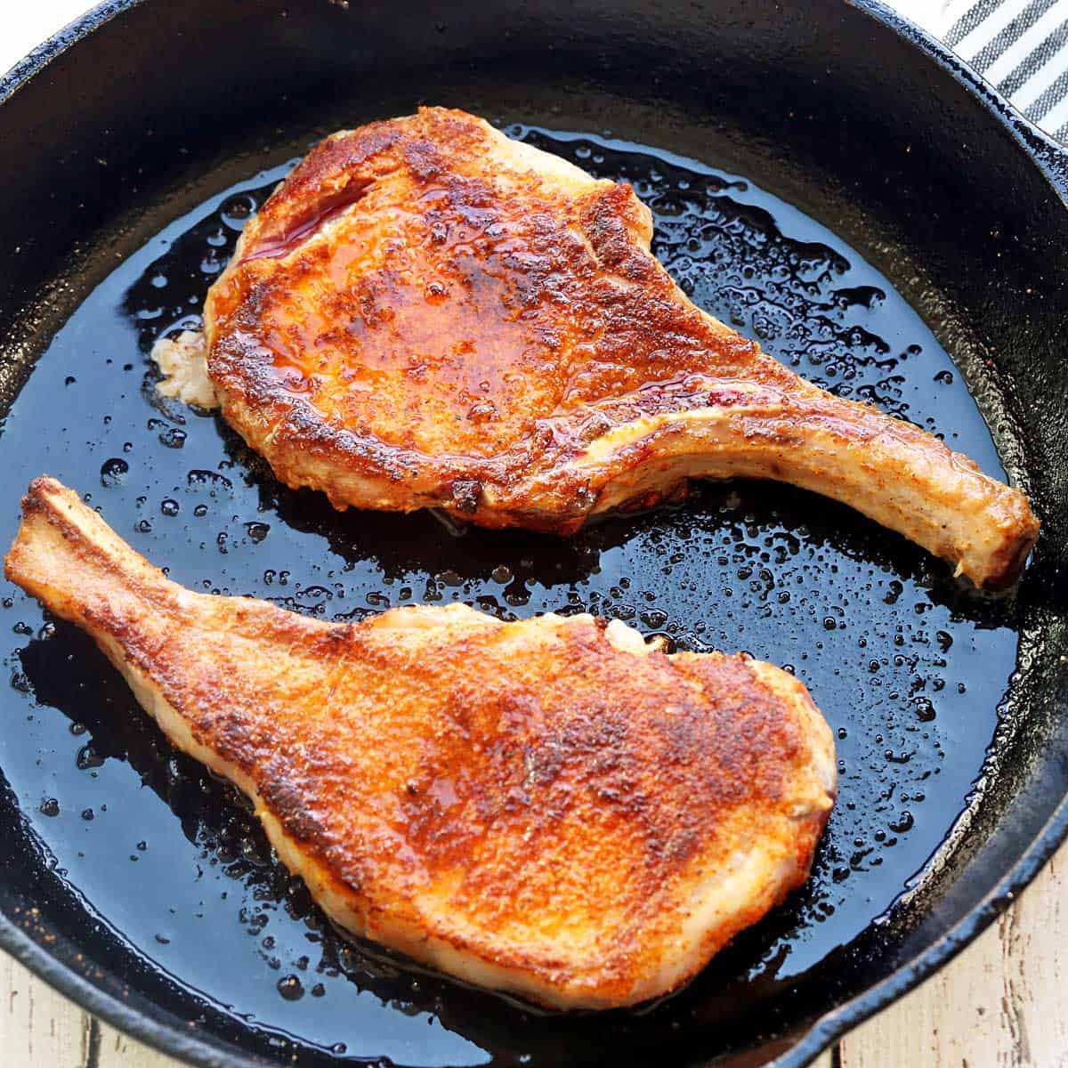 Thin pork chops served in a cast-iron skillet. 