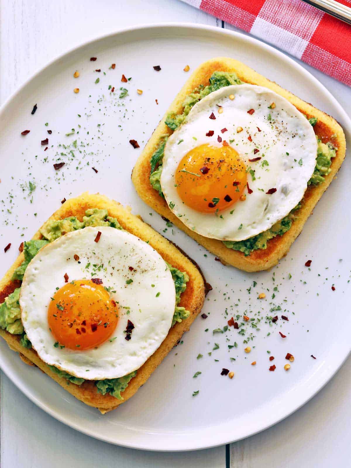 Two pieces of low-carb avocado toast topped with fried eggs. 