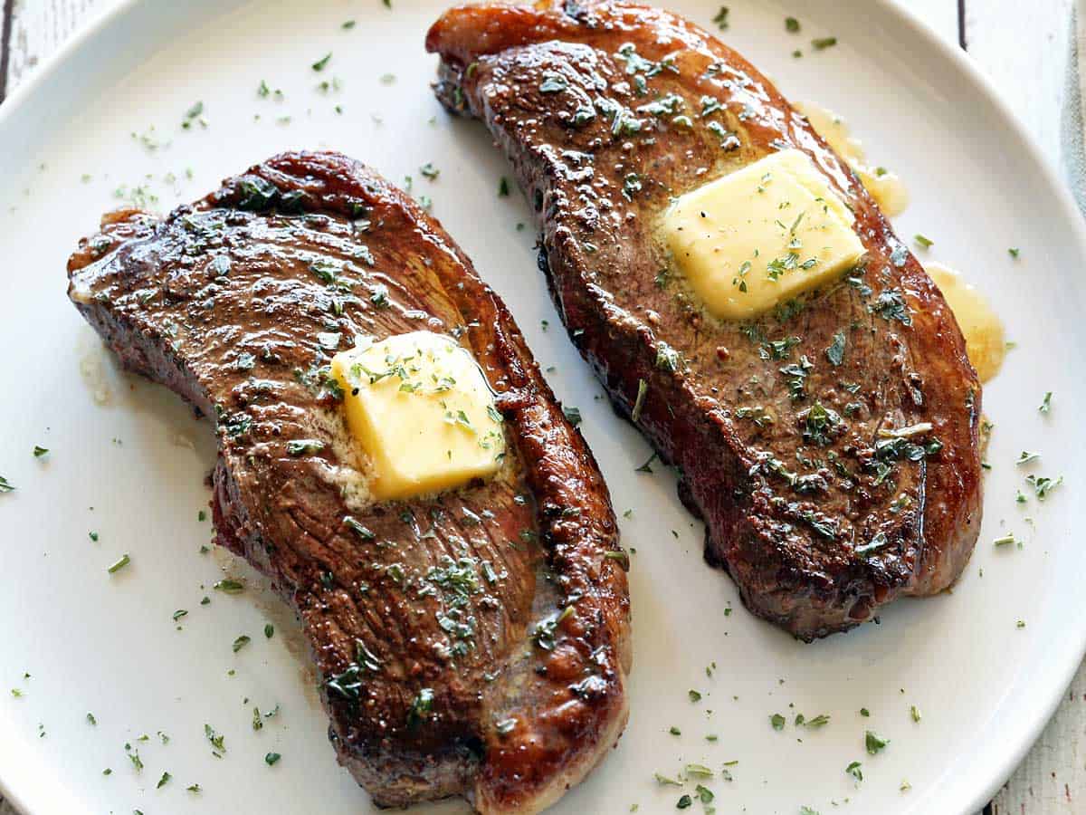 Two picanha steaks topped with butter. 