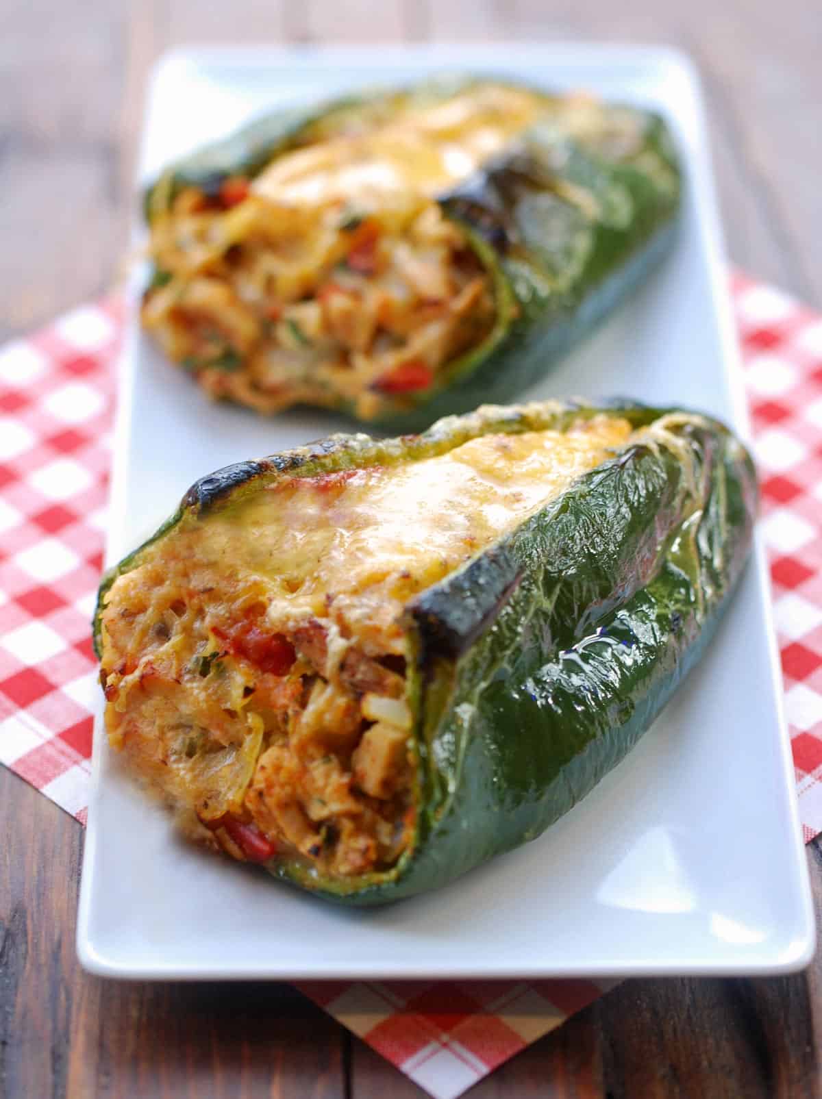 Stuffed poblano peppers served on a white plate with a napkin.