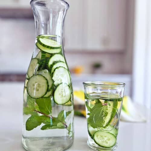 Cucumber water served in a pitcher and in a glass.