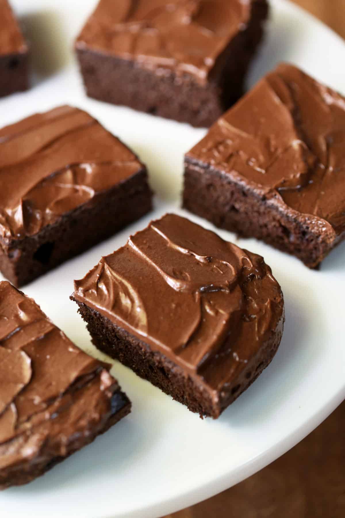 Keto chocolate cake pieces with chocolate frosting served on a white plate.