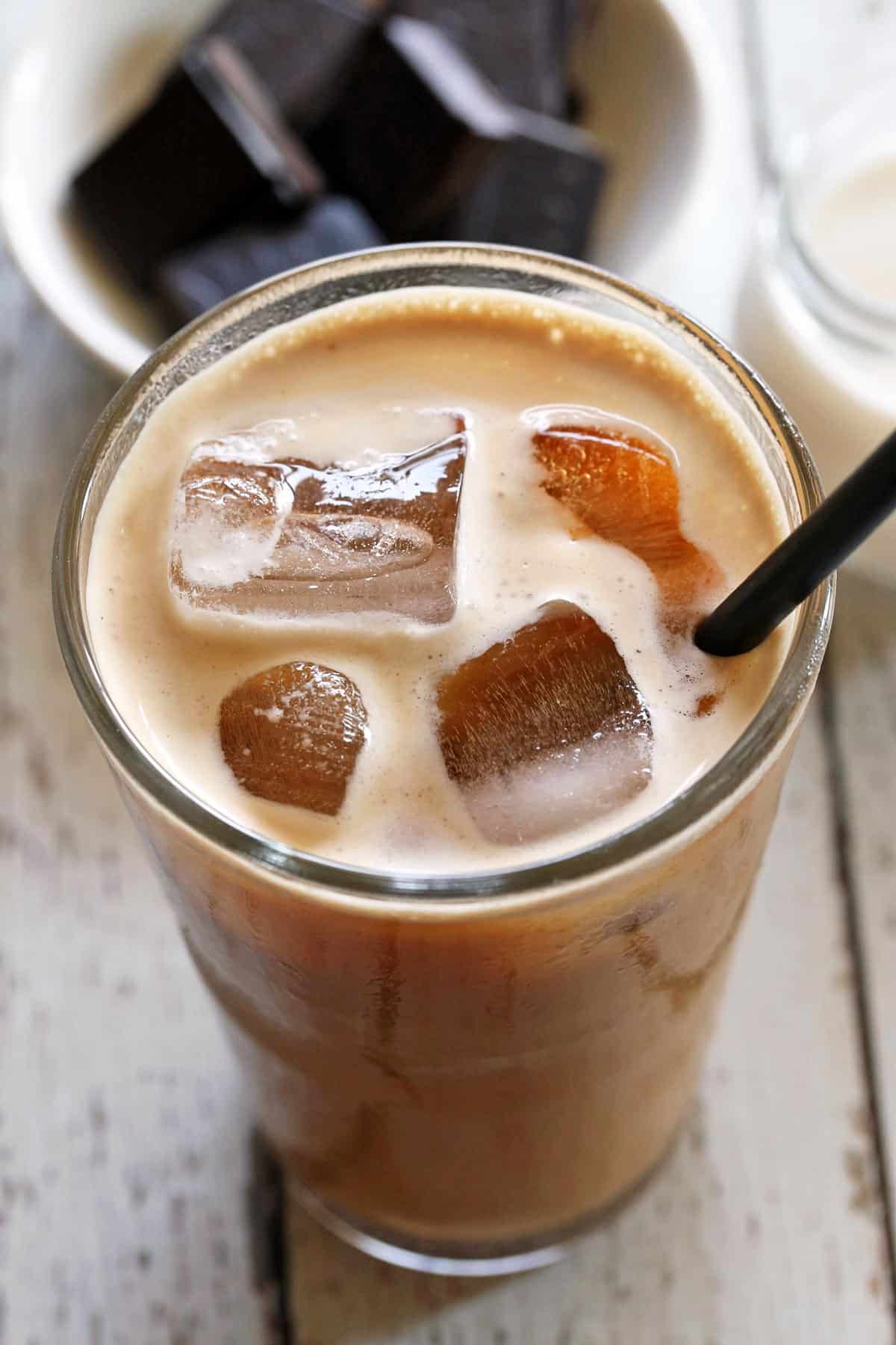 Iced coffee served in a tall glass with a straw. 