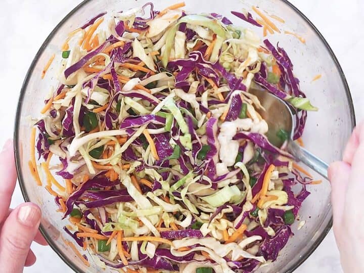 Mixing Asian cabbage salad with a large spoon.