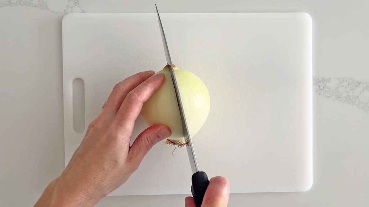 Cutting an onion in half through the root end. 