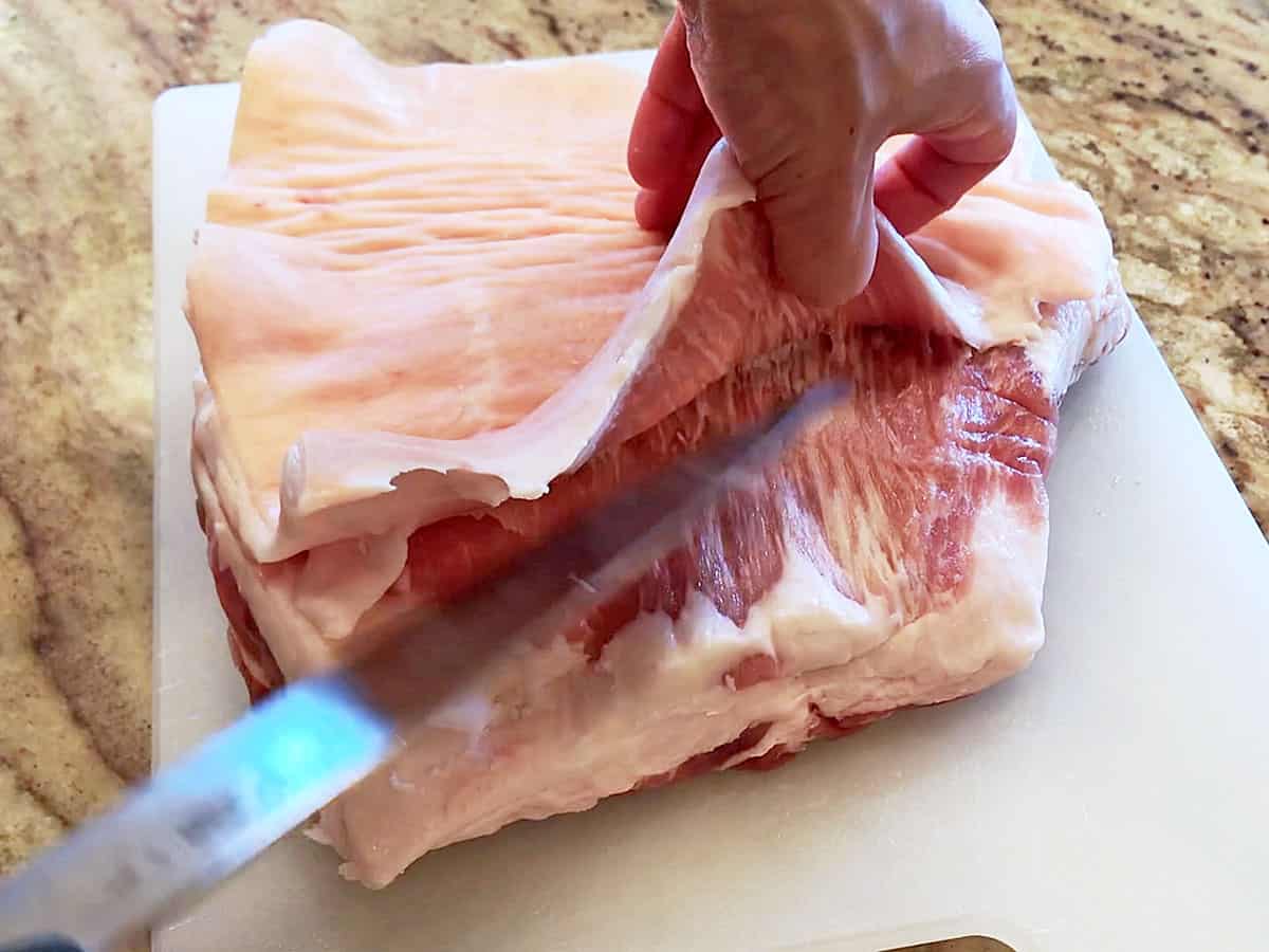 Removing pork belly skin with a chef's knife. 