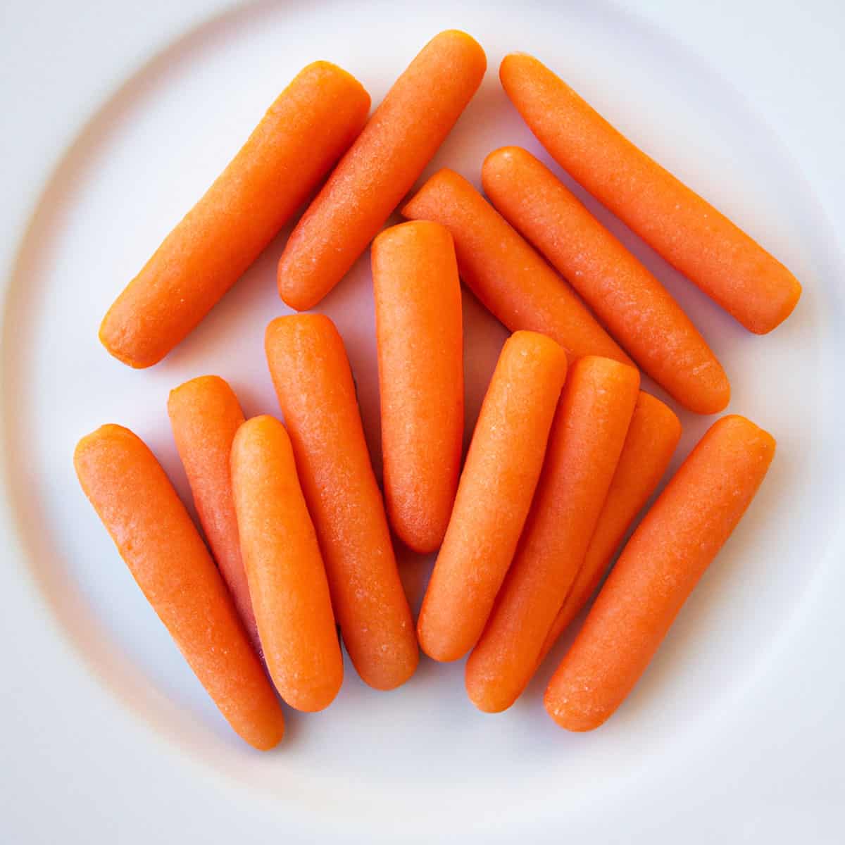 Baby carrots on a white plate. 
