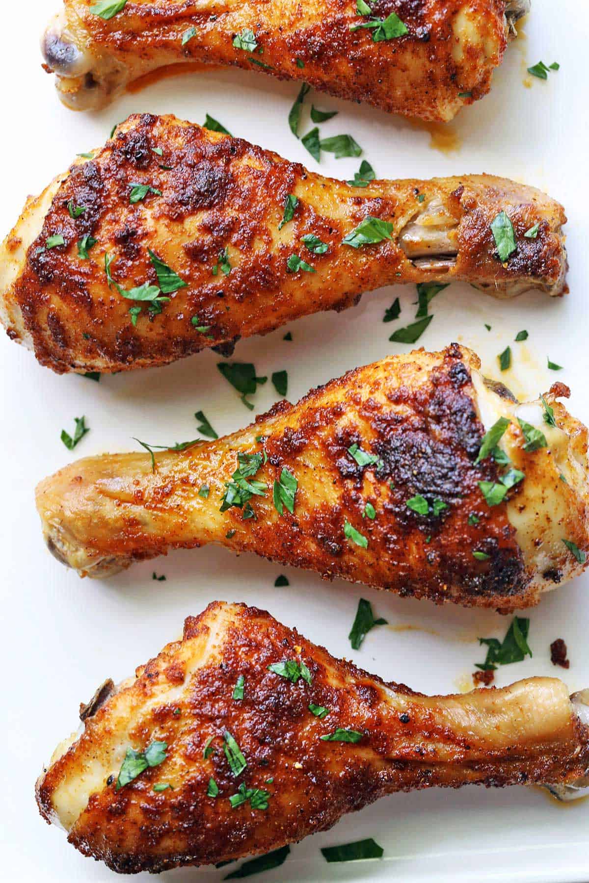 Baked chicken drumsticks topped with chopped parsley. 