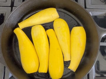 Yellow squash in skillet, flesh side down.