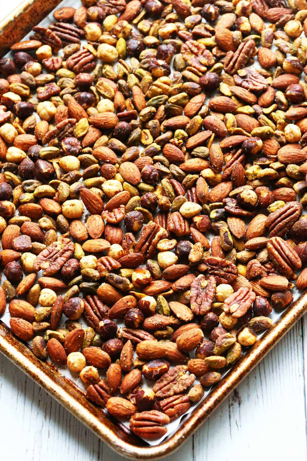 Roasted nuts on a parchment-lined baking sheet. 
