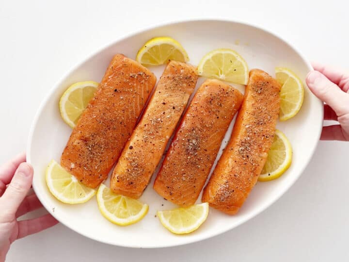 Salmon fillets and lemon slices arranged on a baking dish.