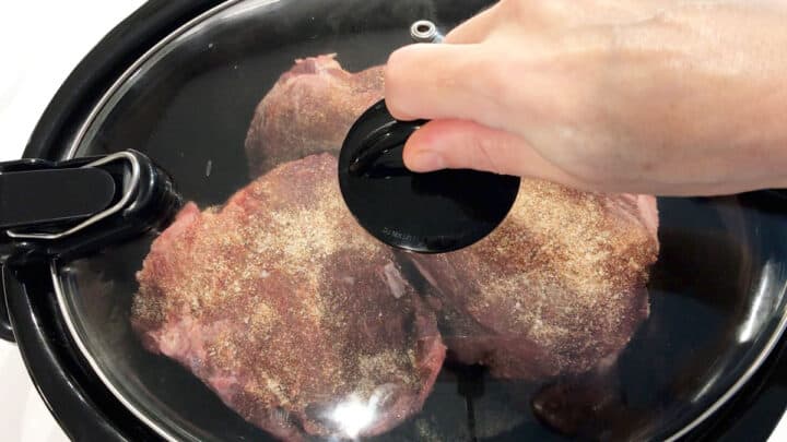 Covering the slow cooker with a lid.