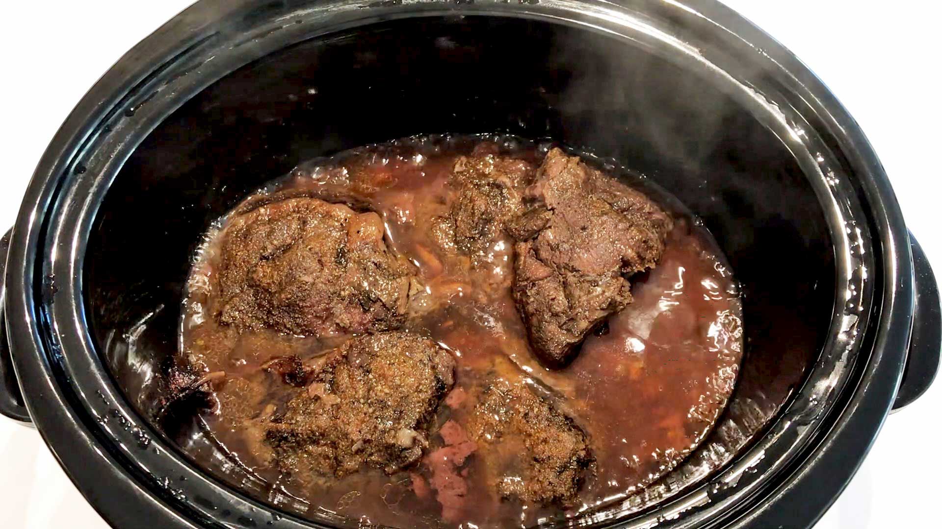 THe beef cheeks are ready in the slow cooker pan. 