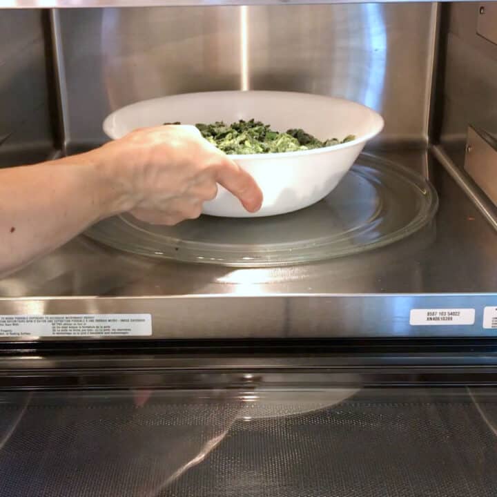Defrosting frozen spinach in the microwave.