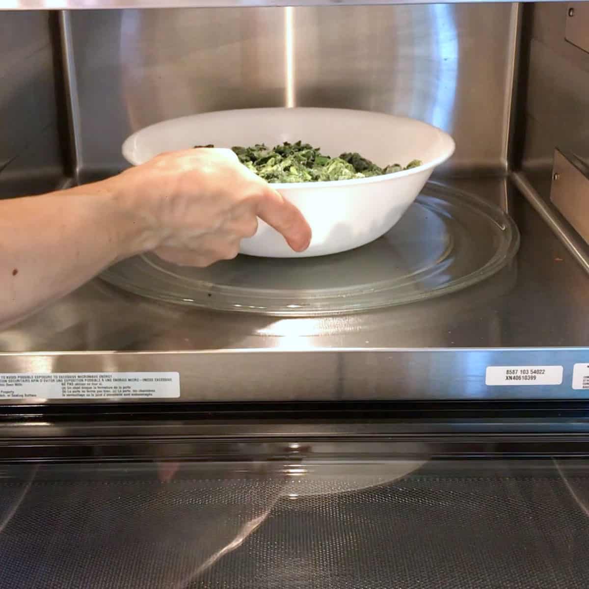 Defrosting the frozen spinach in the microwave. 